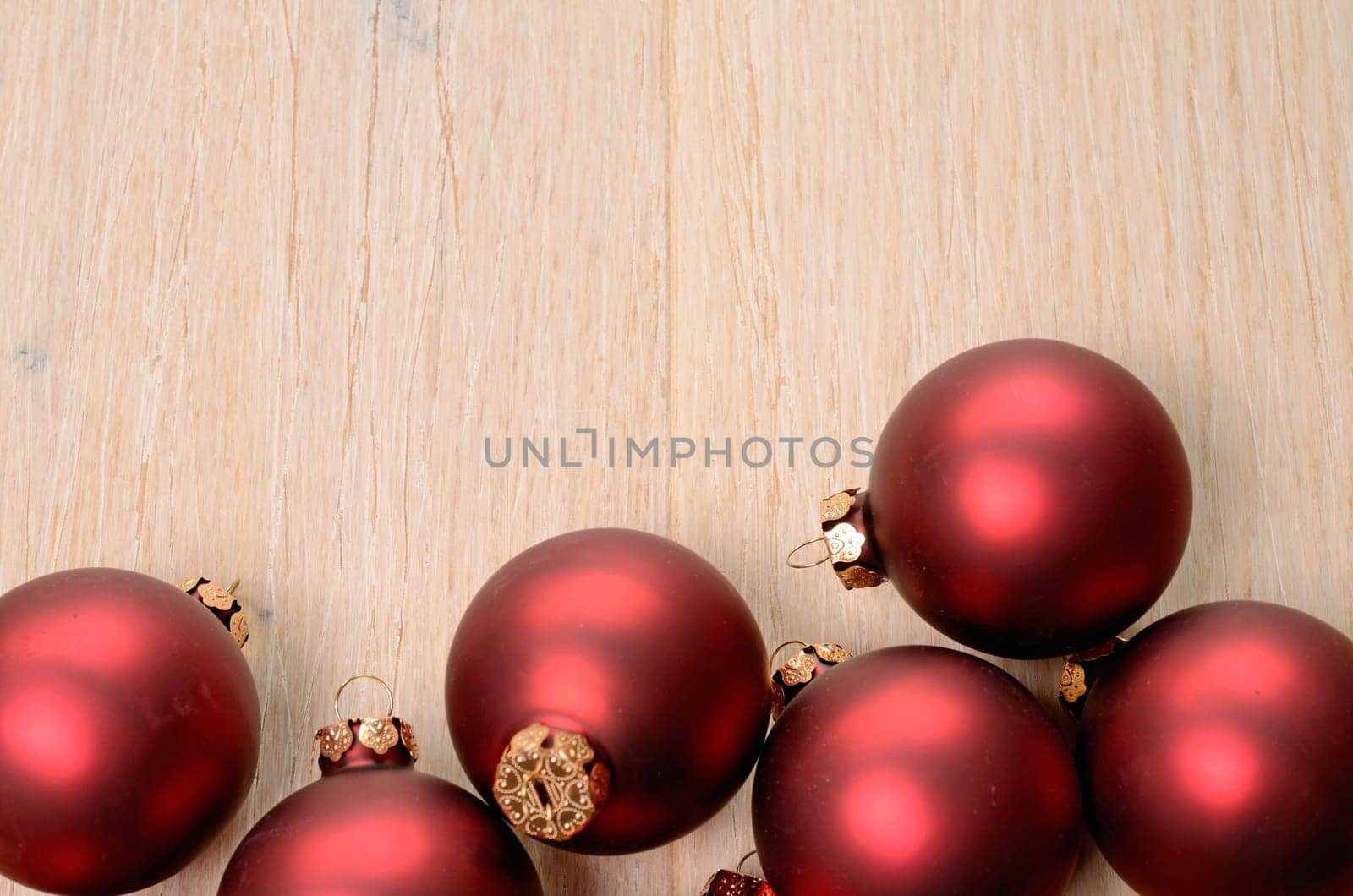 Red Christmas baubles on a wooden background with space for your text