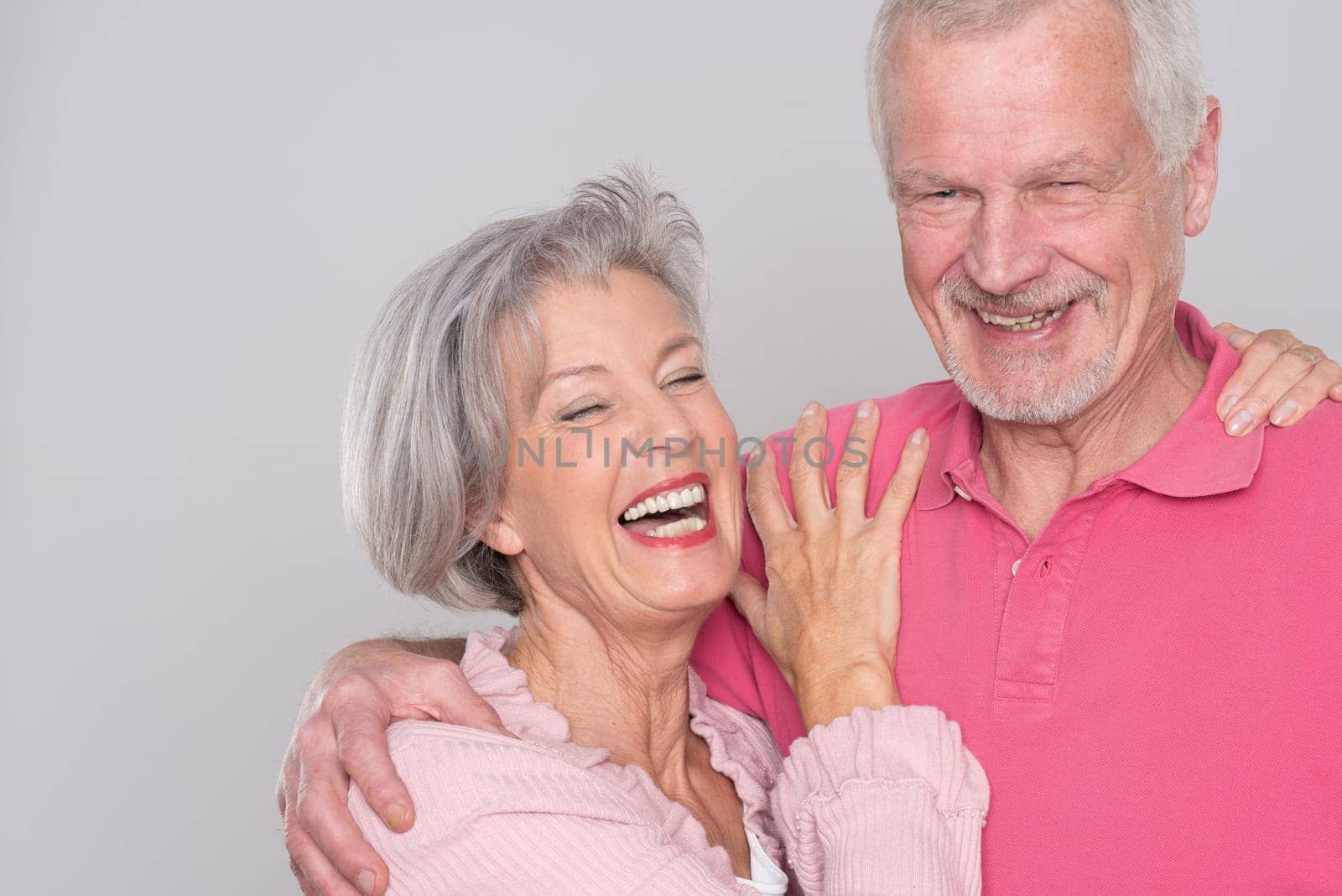 Happy senior couple against a grey background