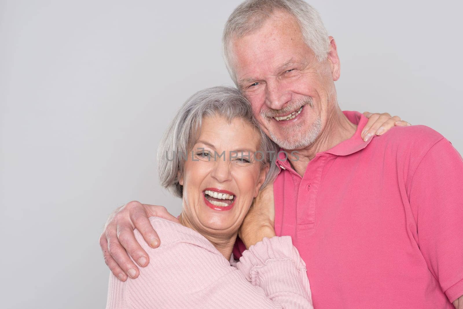Happy senior couple against a grey background