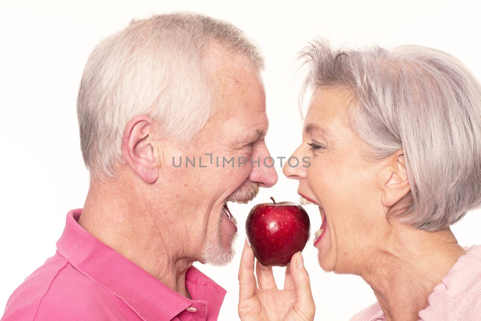Senior couple with an apple against a white background