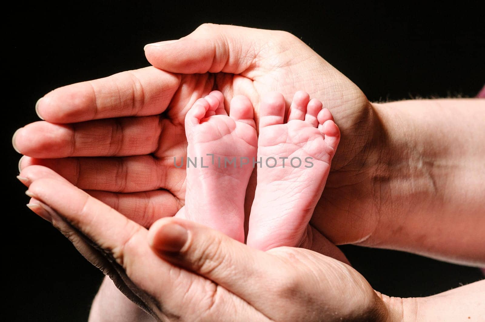 Mamma's haende include tame and begging babies little fuesse,exposed against a dark background.