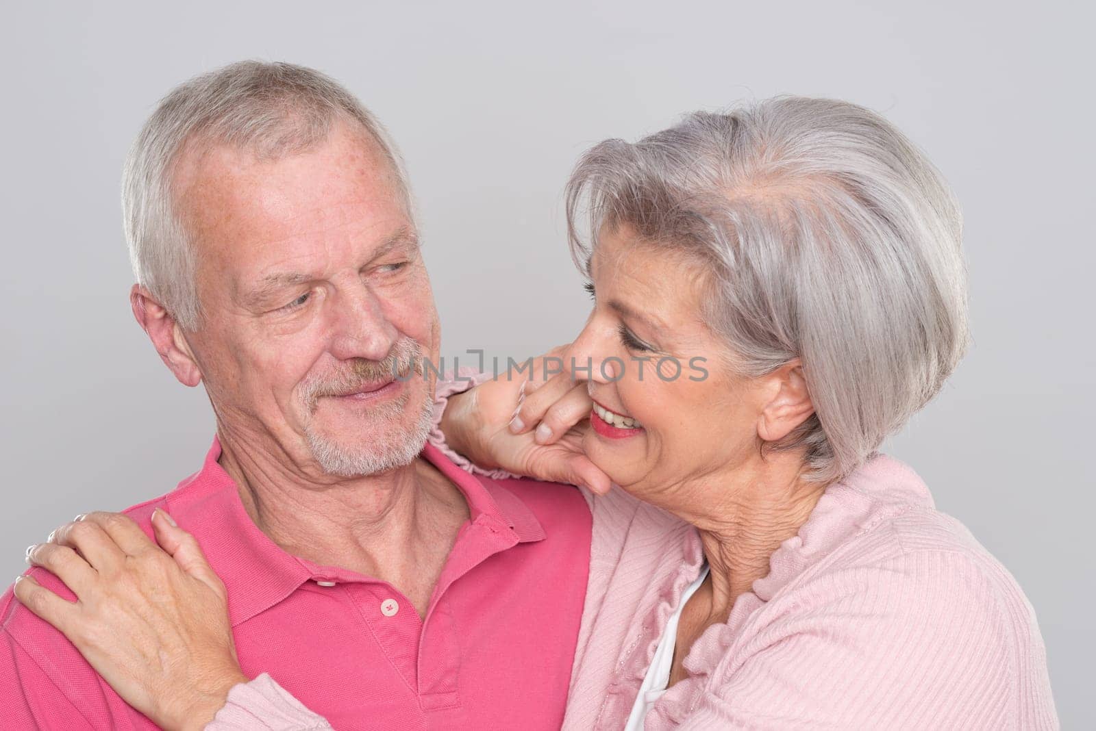 Happy senior couple against a grey background