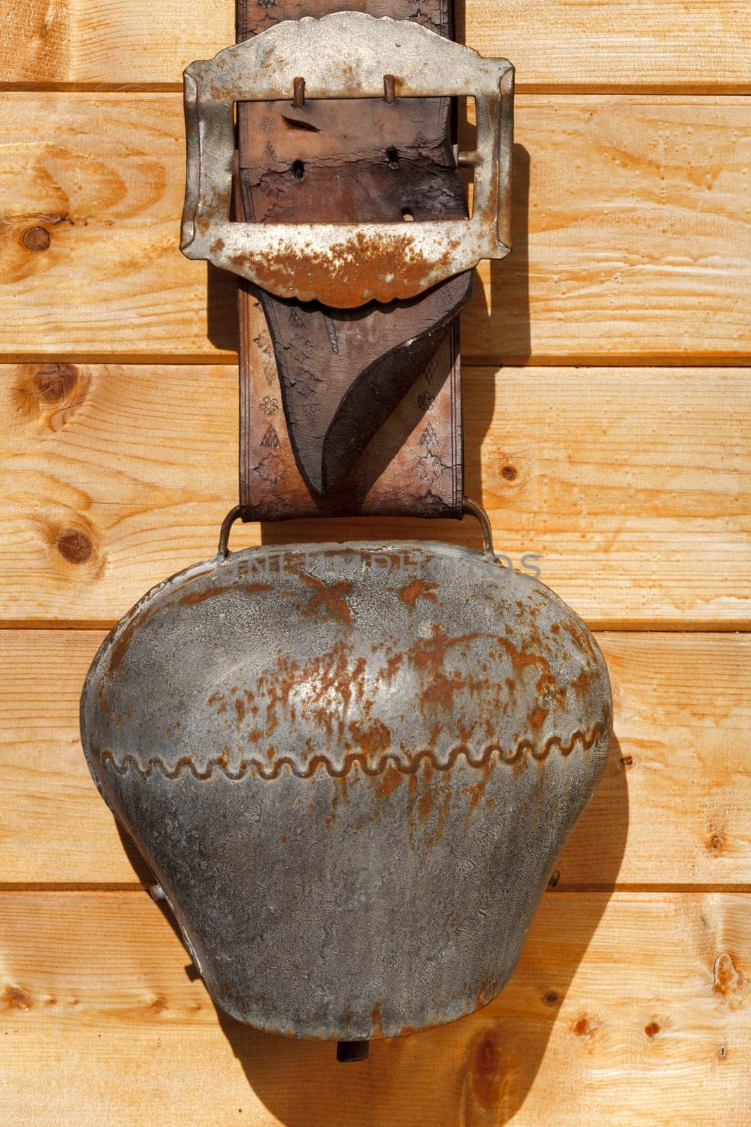 Very old cowbell hangs on wooden hut