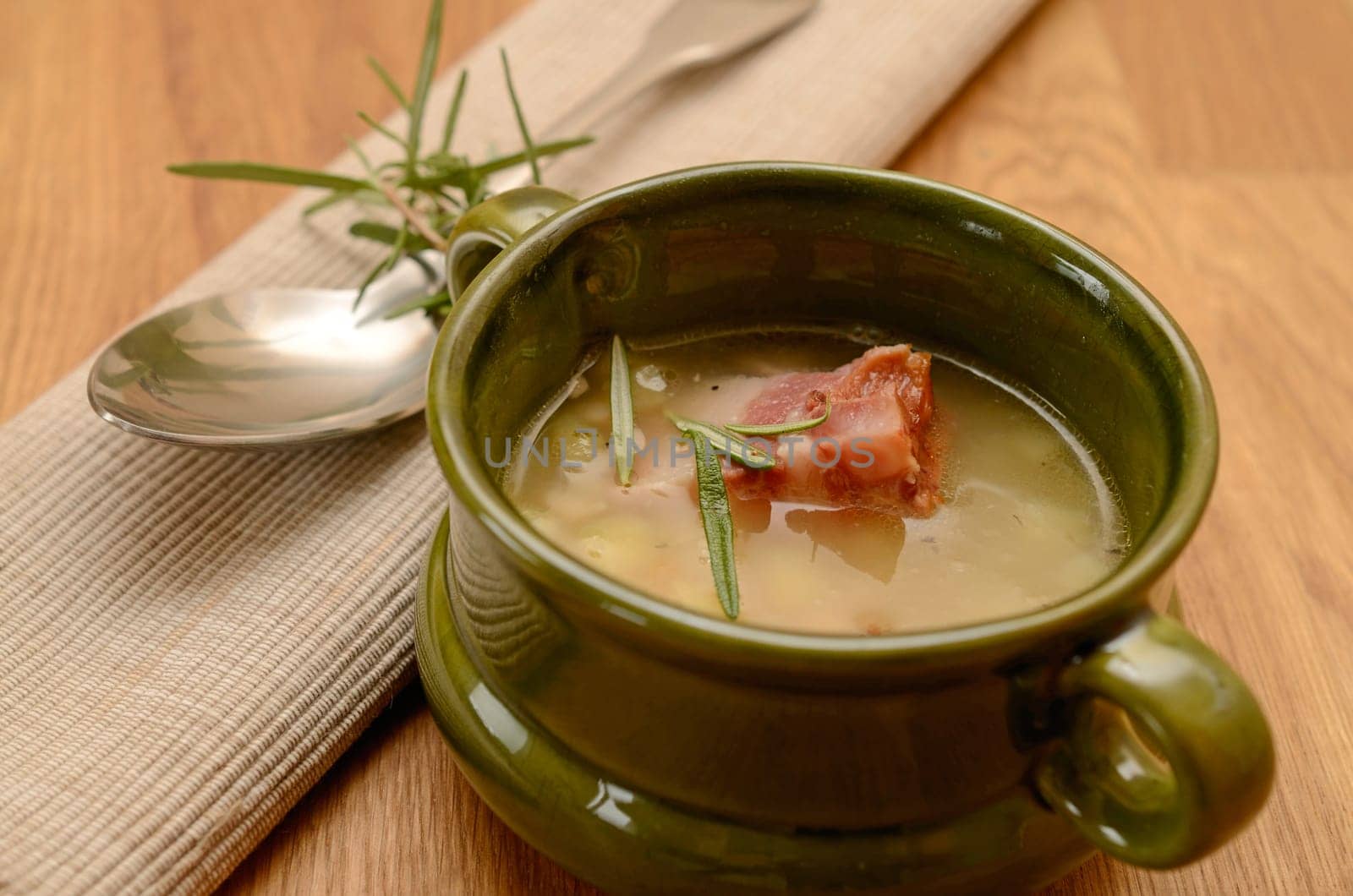 Green ceramic bowl with bean soup and bacon