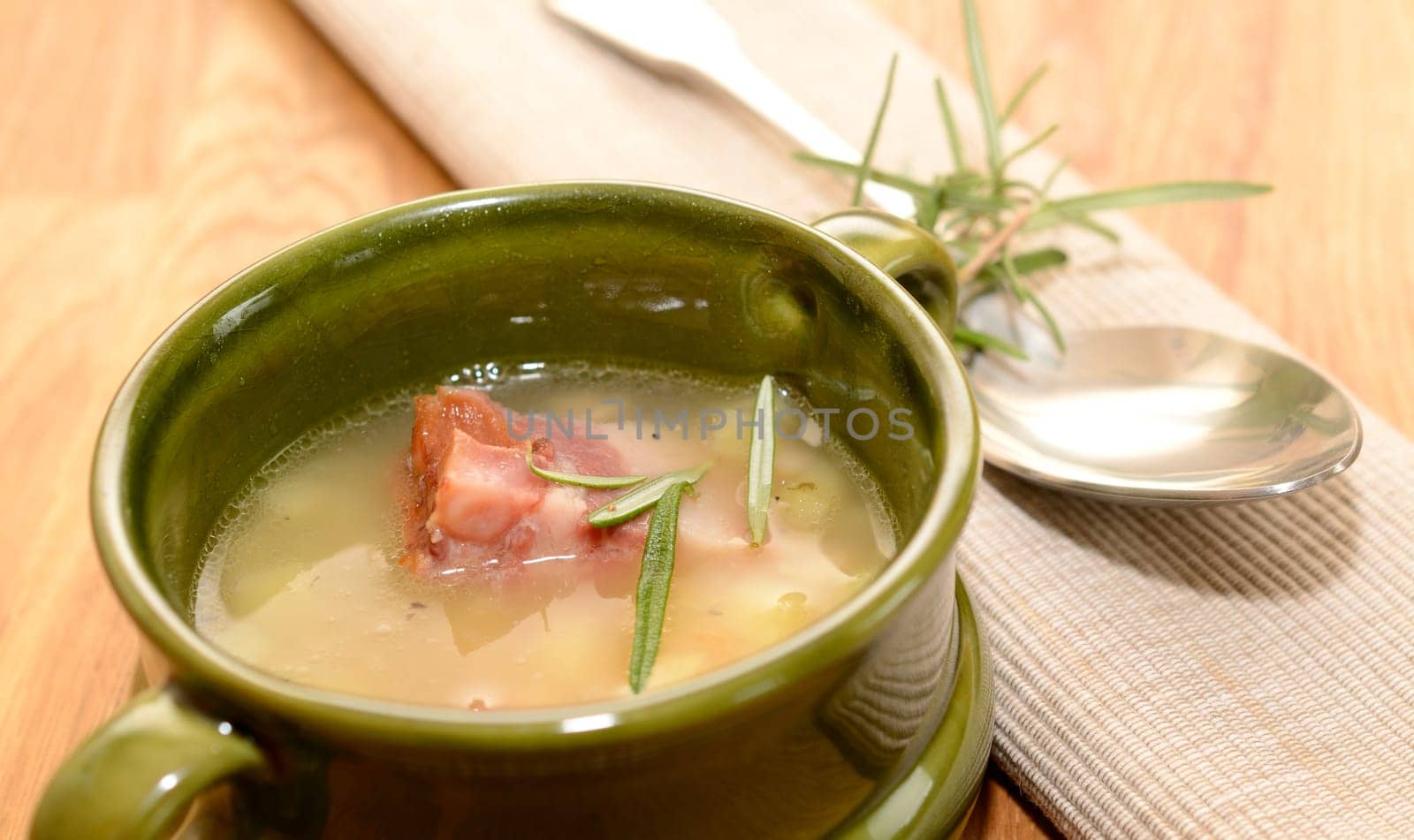 Green ceramic bowl with bean soup and bacon