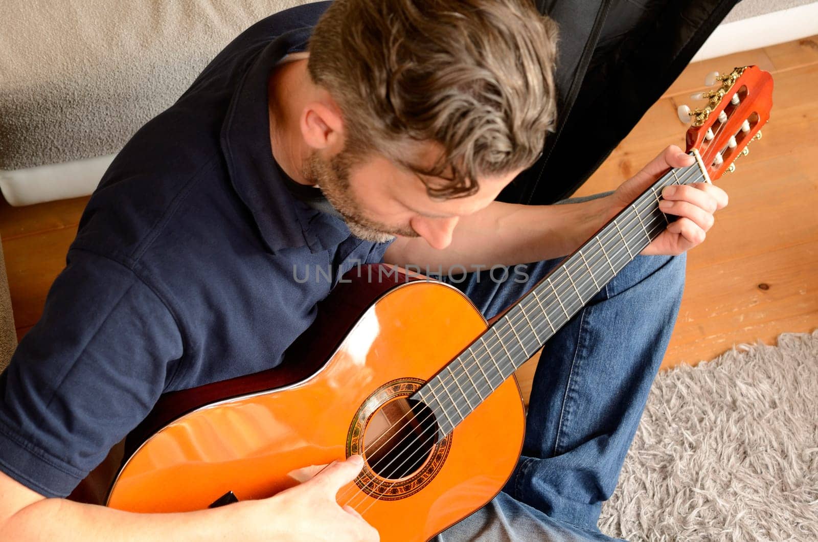 Young man playing guitar on a wooden floor