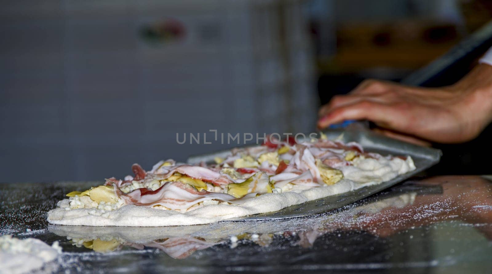 Preparing pizzas with mozzarella, bacon and artichokes for cooking