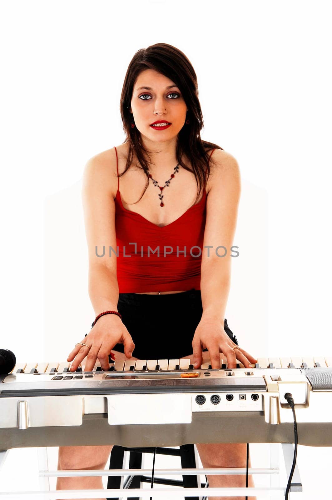 A young brunette woman playing the keyboard for white background..
