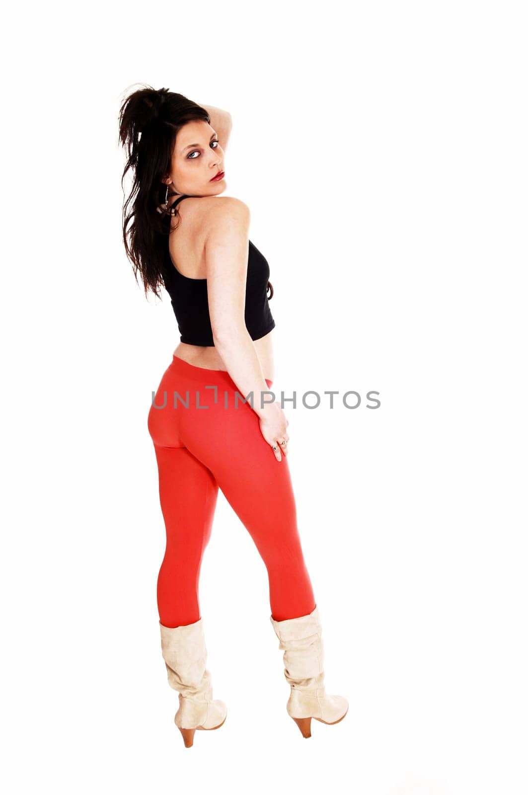 A pretty woman in a black top and red tights standing from the back.in boots for white background..