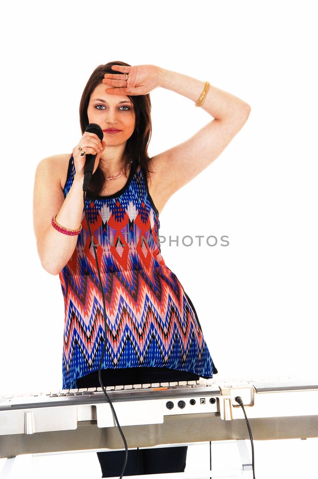 A beautiful young woman standing for a keyboard with a mic in her hand.and singing for white background..