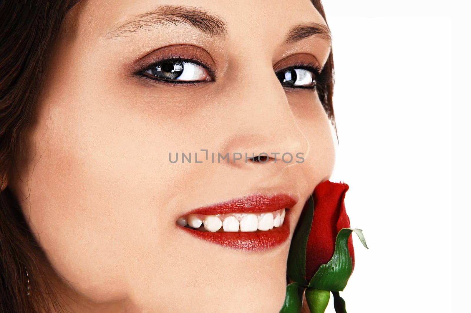 A extreme closeup pictures of the face of a beautiful young woman, holding.a red rose to her face, for white background..