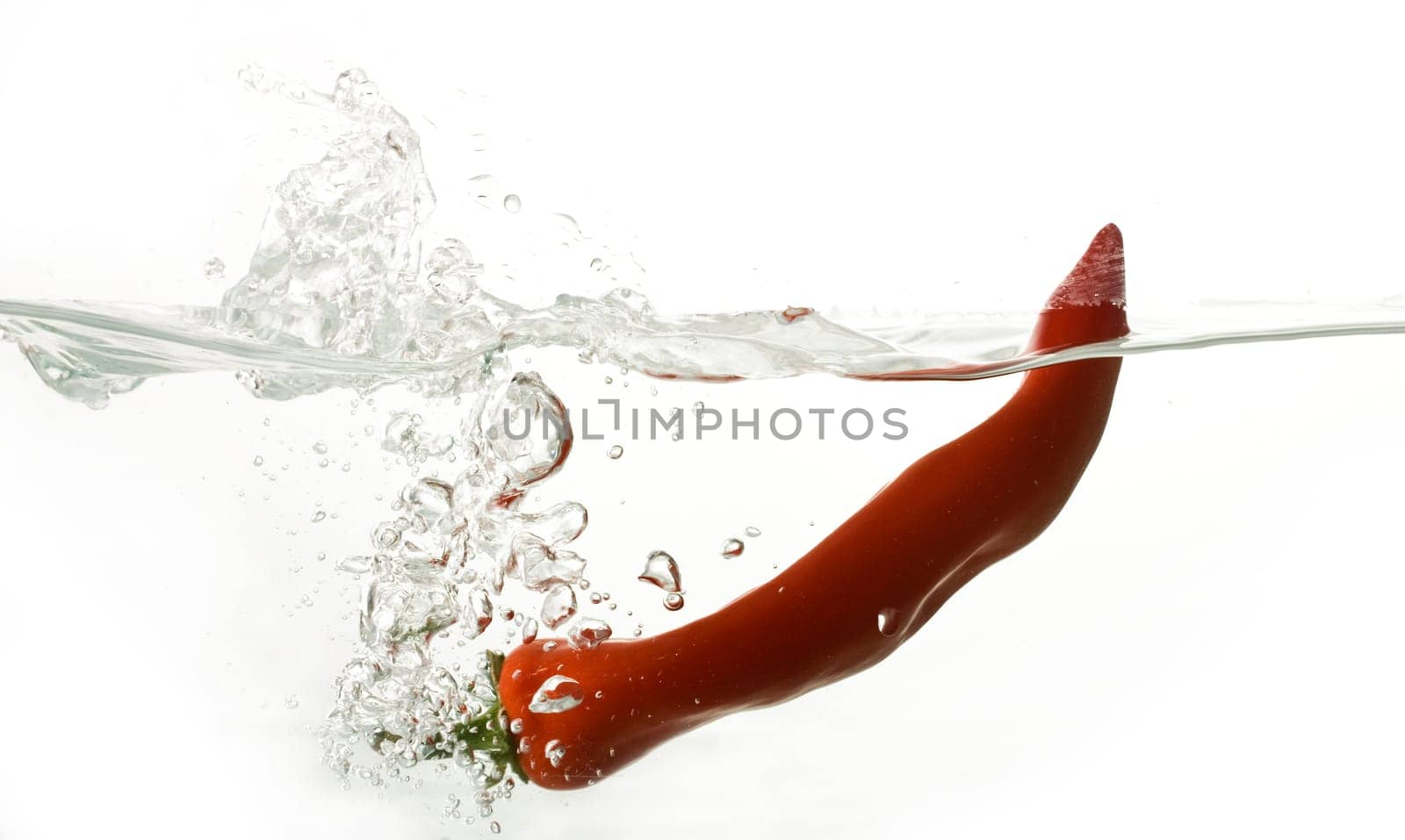 Red pepper splashing into water isolated on white