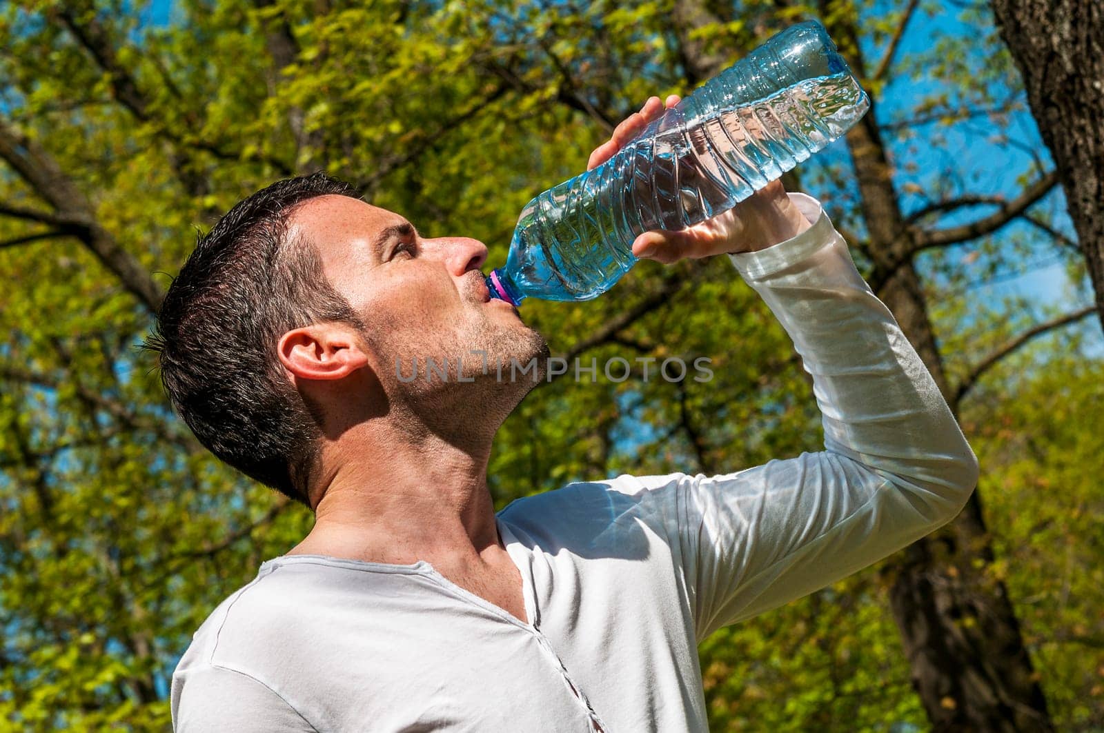 Man is drinking water against a natural background