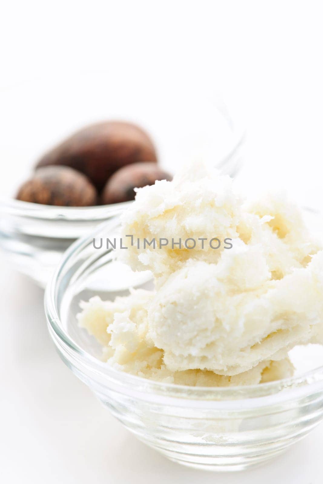 Shea butter and nuts in glass bowls isolated on white