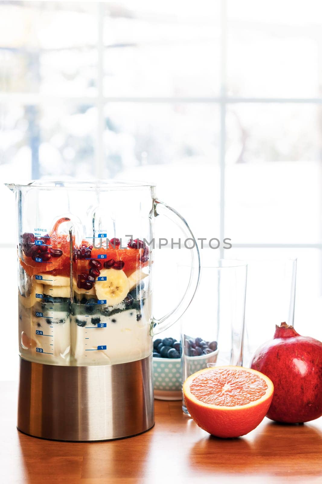Healthy smoothie ingredients in blender with fresh fruit ready to blend on kitchen table