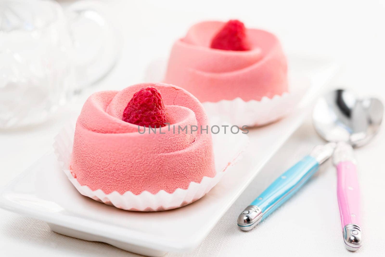 Two pink raspberry mousse desserts on a plate