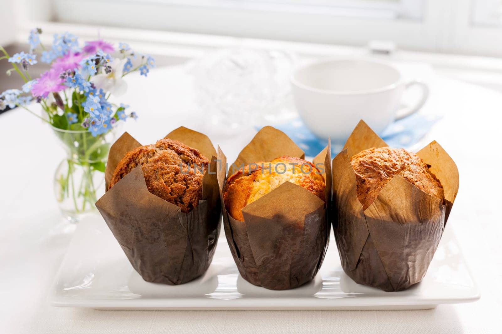 Breakfast table with three muffins in brown paper baking cups