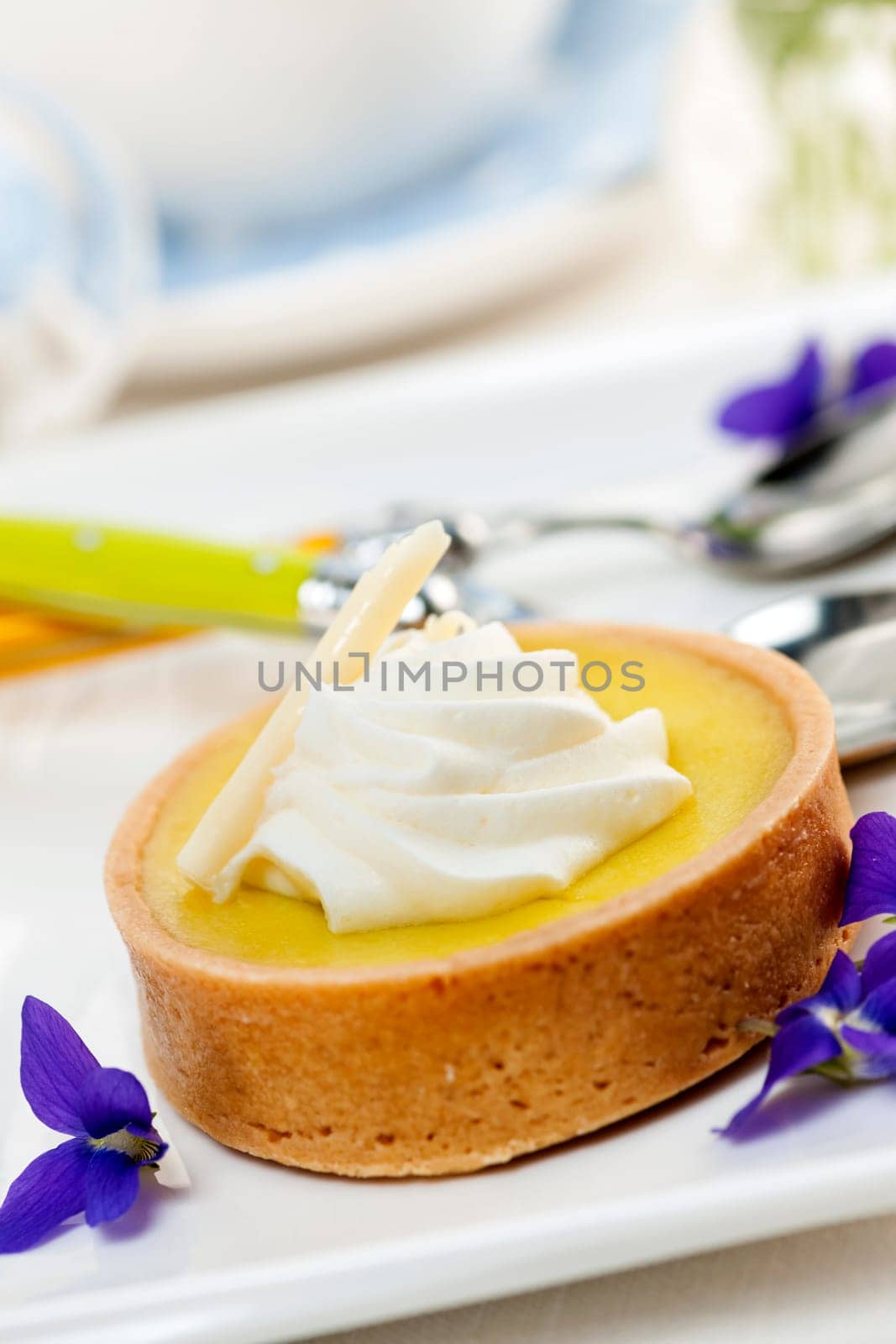 Fresh gourmet lemon dessert tart with edible violet flowers garnish