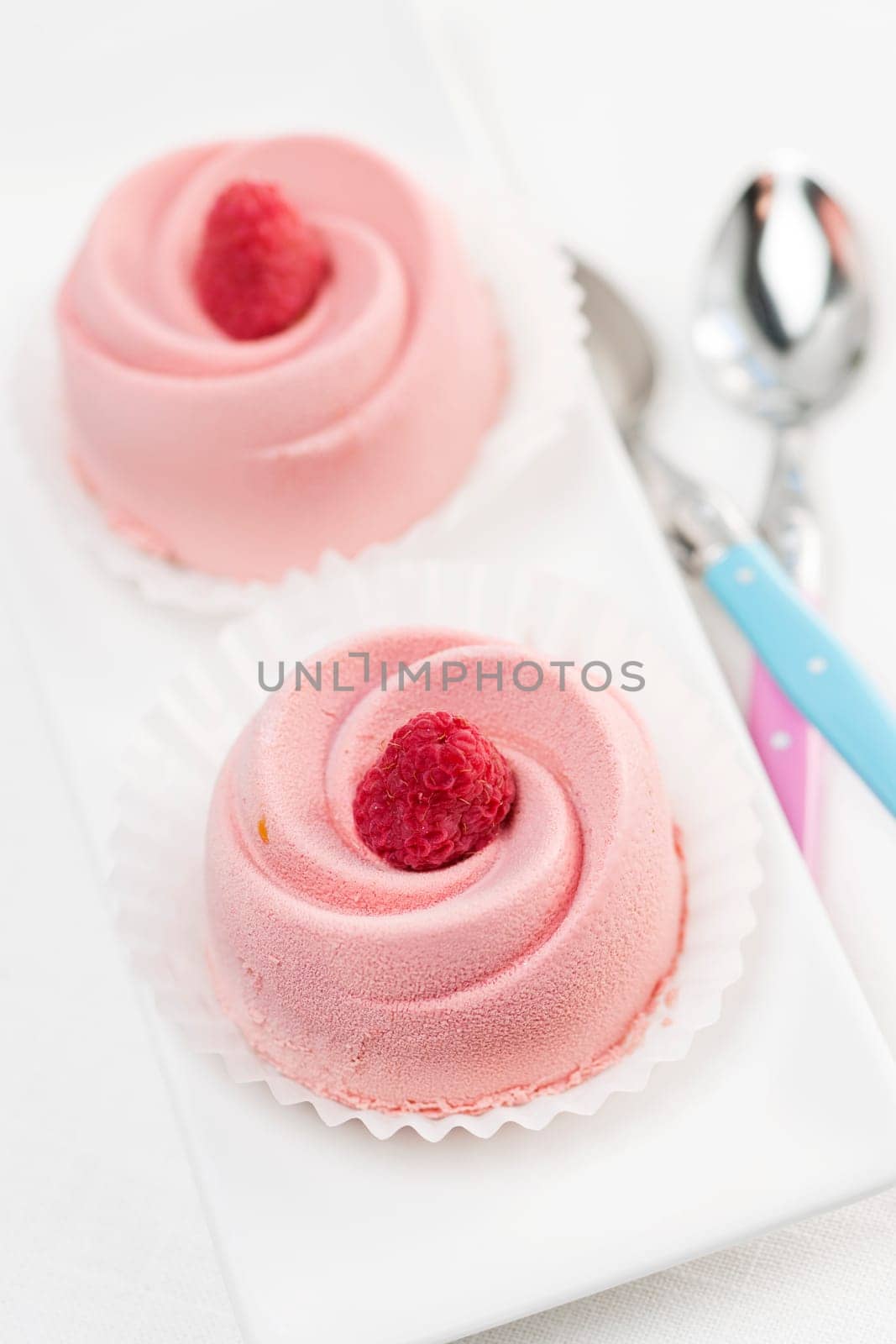Two pink raspberry mousse desserts on a plate