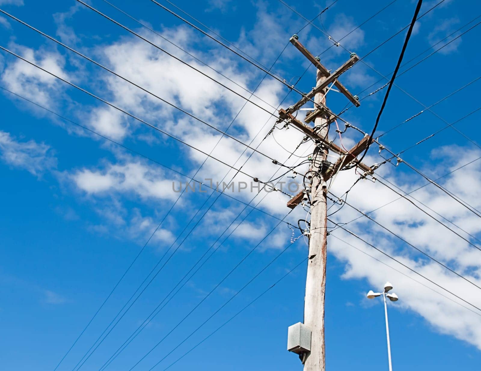 Australian electricity grid with power pole and power lines against blue sky
