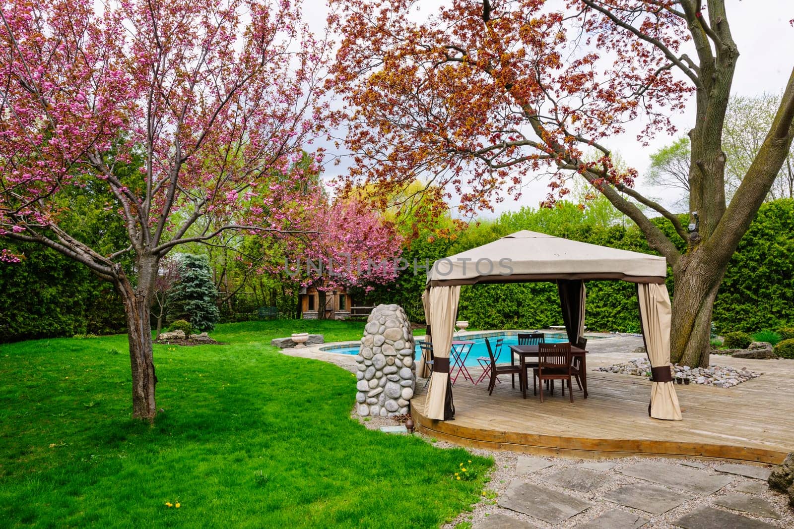 Residential  backyard with gazebo, deck, stone patio and swimming pool