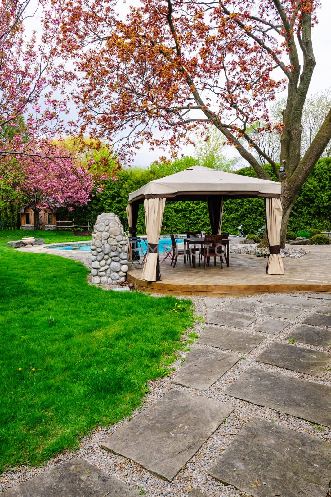 Residential  backyard with gazebo, deck, stone patio and swimming pool