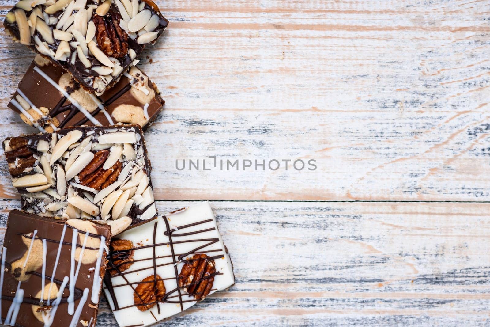 Assorted chocolate caramel bark pieces arranged on wooden background from above with copy space
