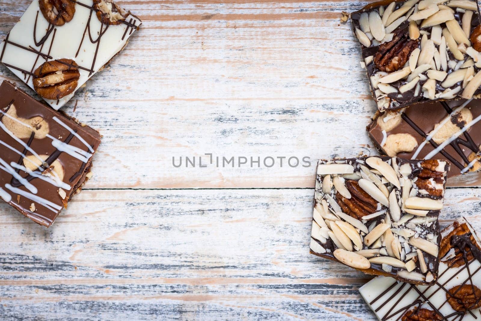Assorted chocolate caramel bark pieces arranged on wooden background from above with copy space