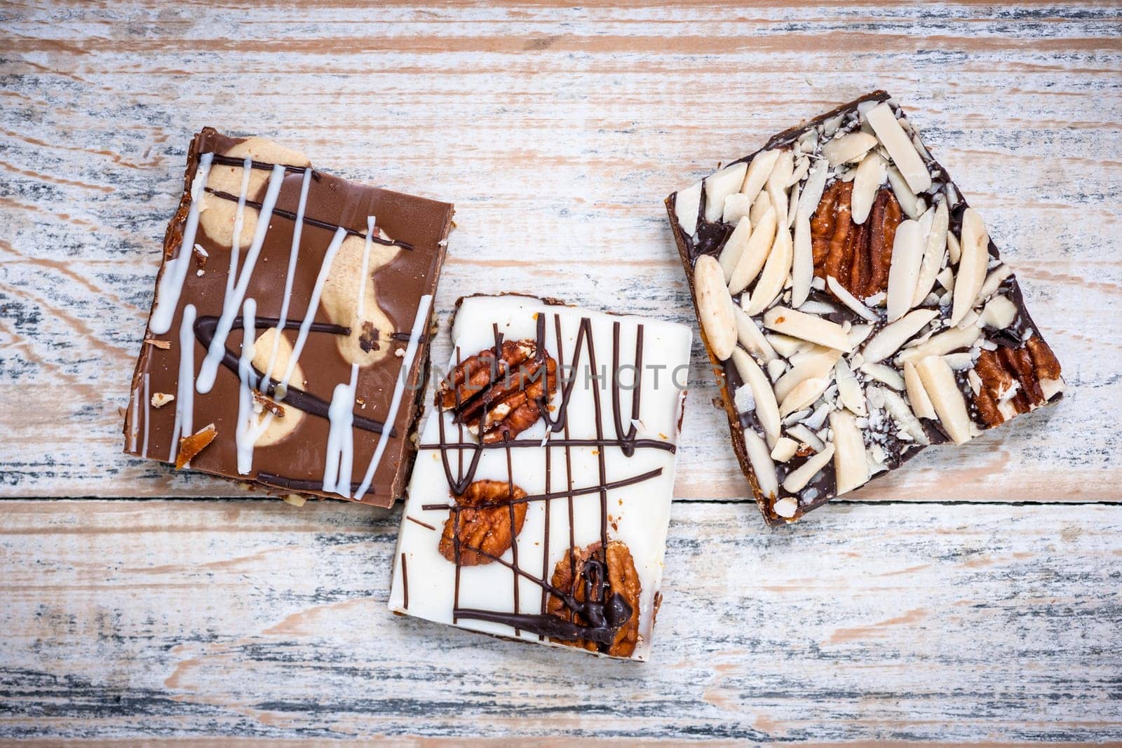 Three assorted chocolate caramel bark pieces as sweet dessert arranged on wooden background from above