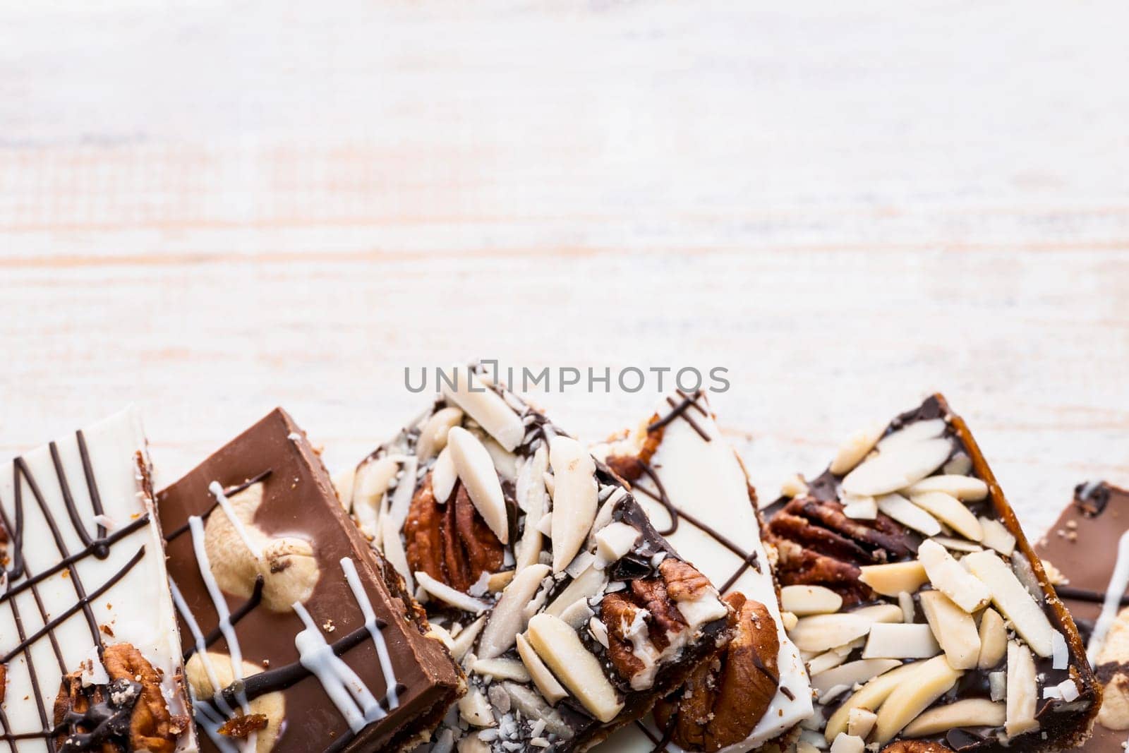 Assorted chocolate caramel bark pieces arranged on wooden background from above with copy space