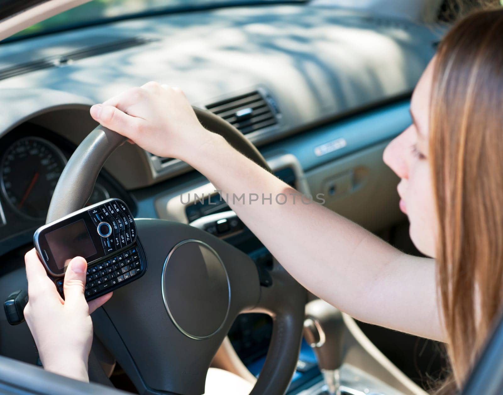 Teenage girl texting on cell phone while driving
