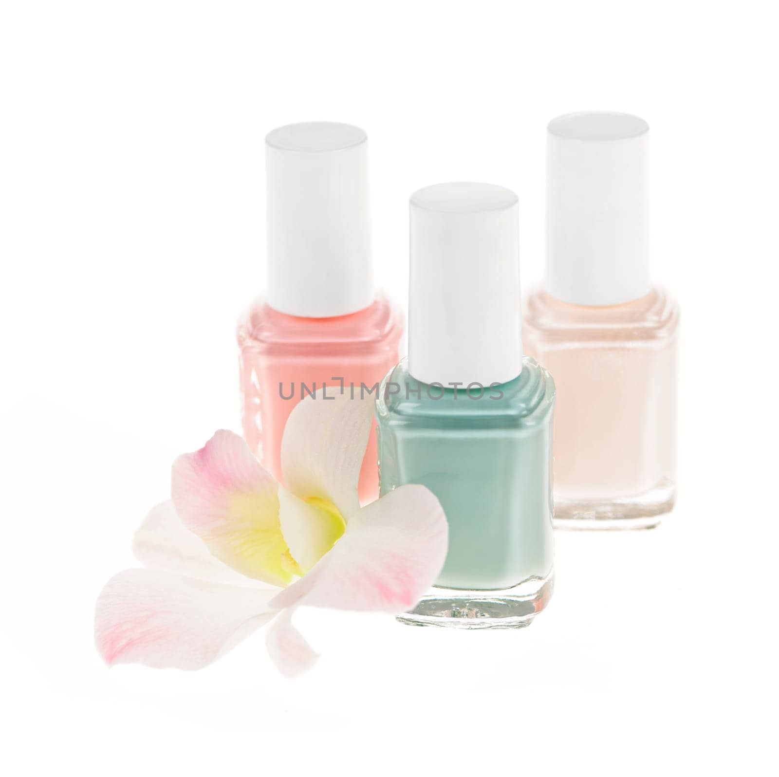 Three nail polish bottles with orchid flower on white background