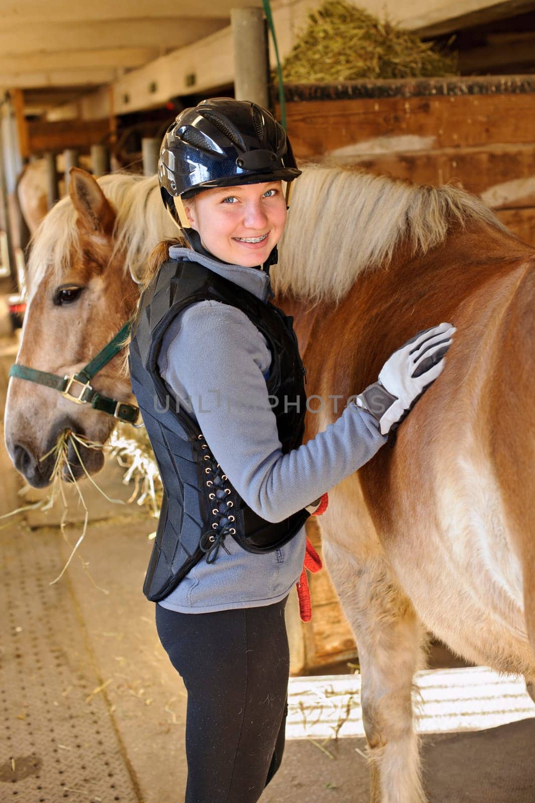 Portrait of teenage girl with horse in stable