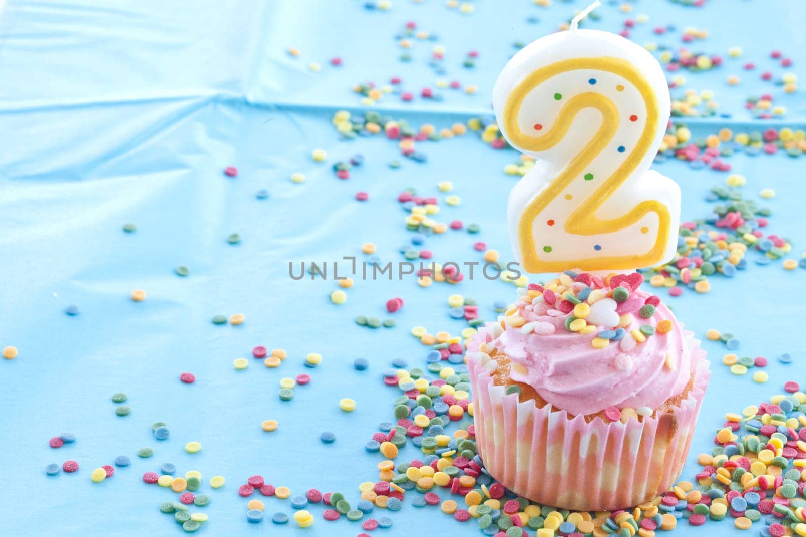 Small colorful cupcake with pink sprinkles for second birthday