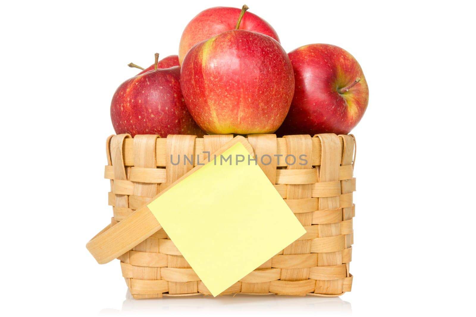 Red apples in woven basket with sticky note. Isolated on the white background