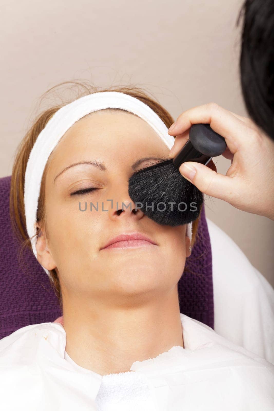 Beautician applies powder with brush