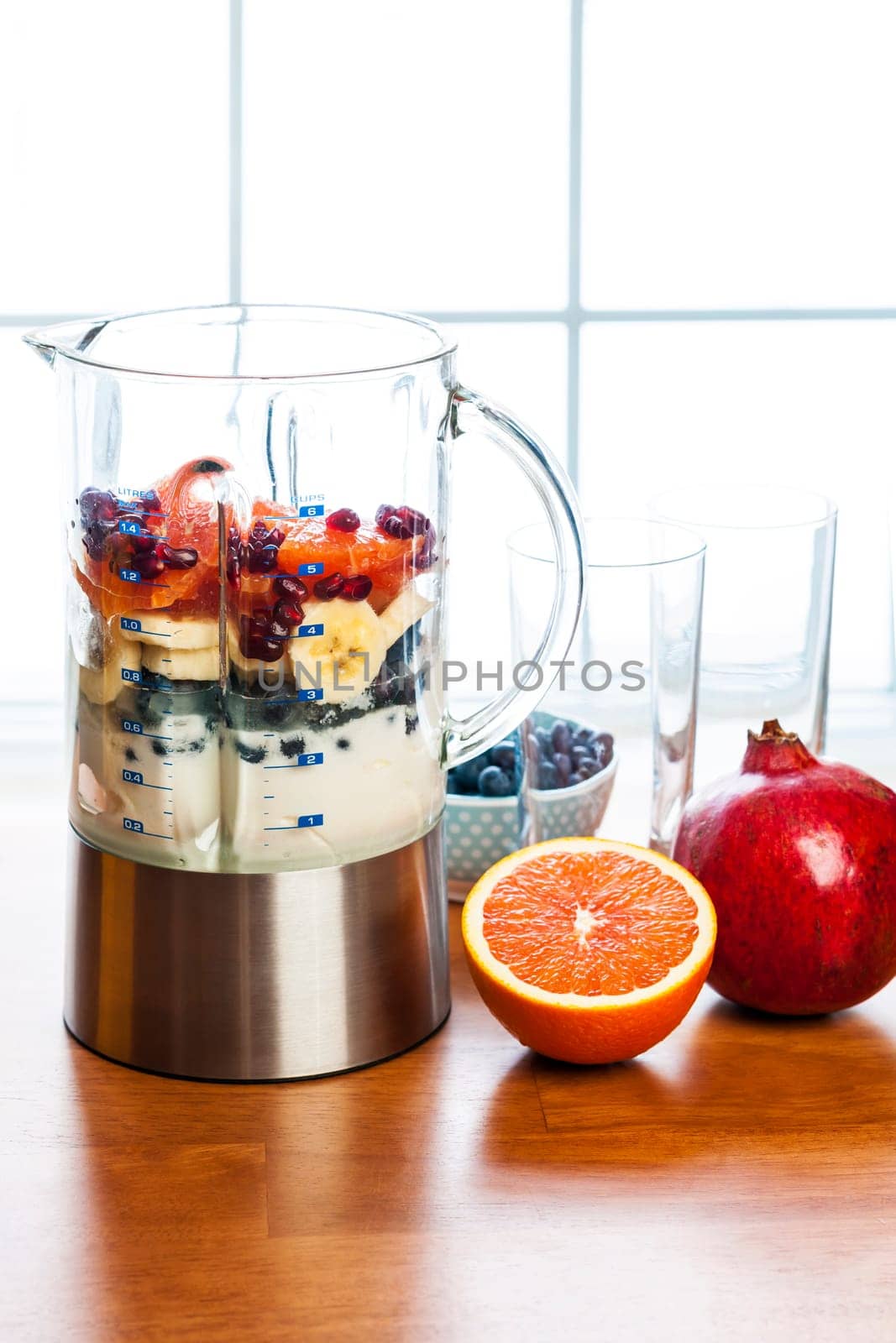Healthy smoothie ingredients in blender with fresh fruit ready to blend on kitchen table