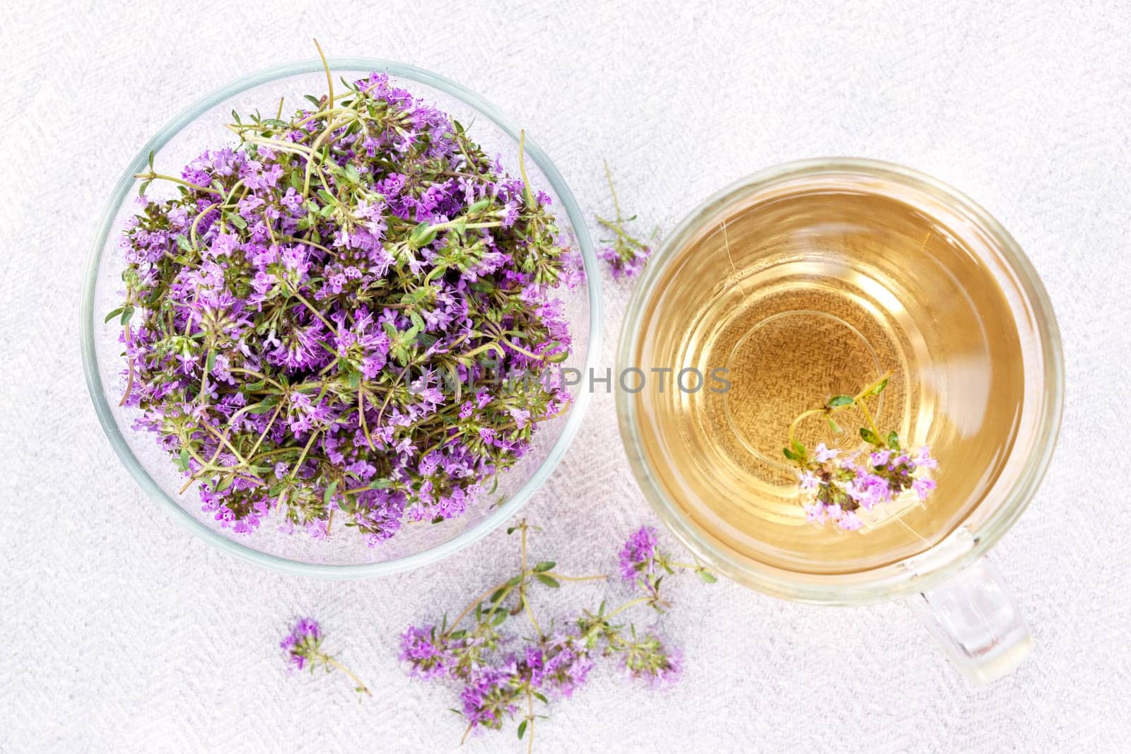 Bowl of fresh thyme sprigs with herbal tea in cup from above
