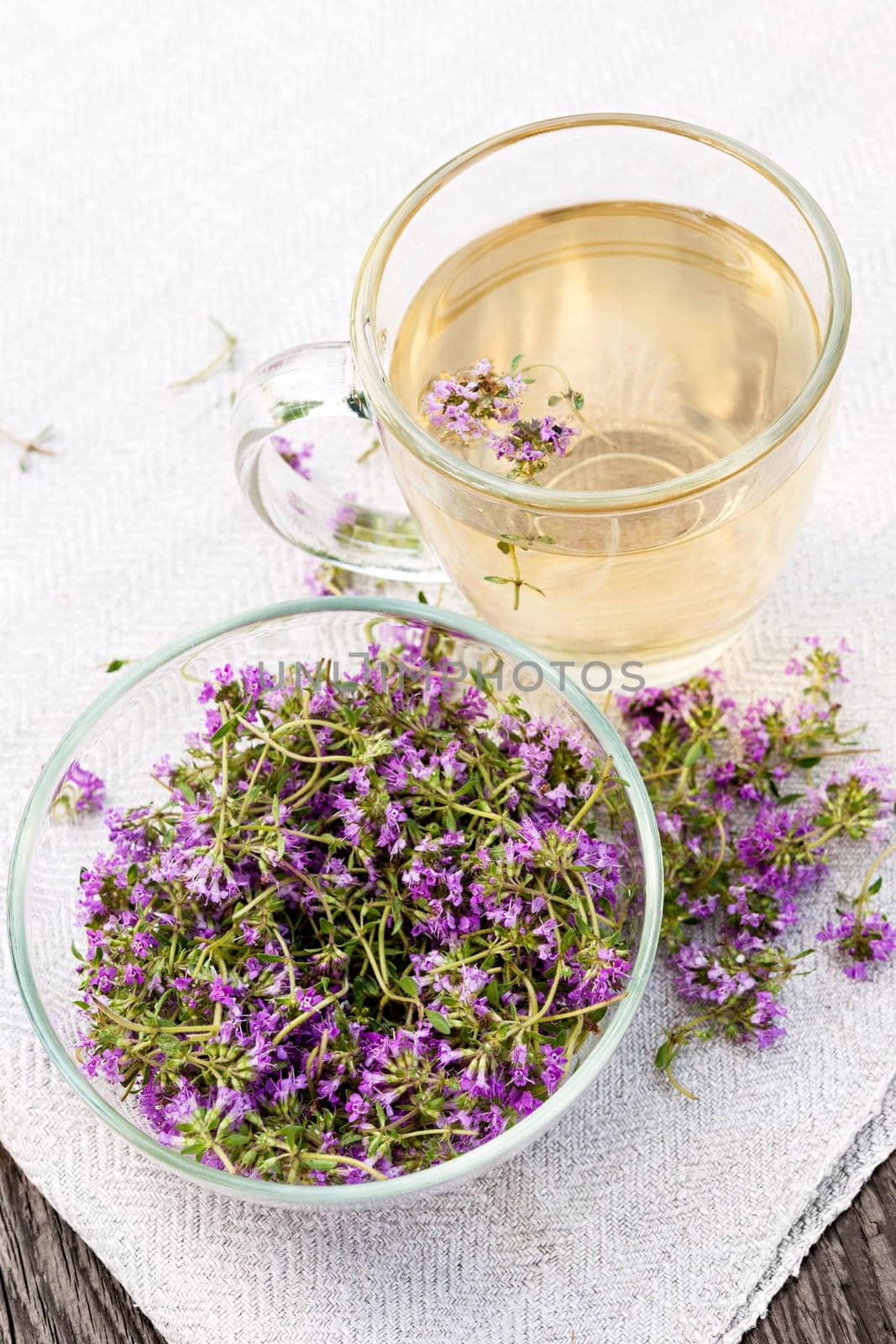 Bowl of fresh thyme sprigs with herbal tea in cup from above