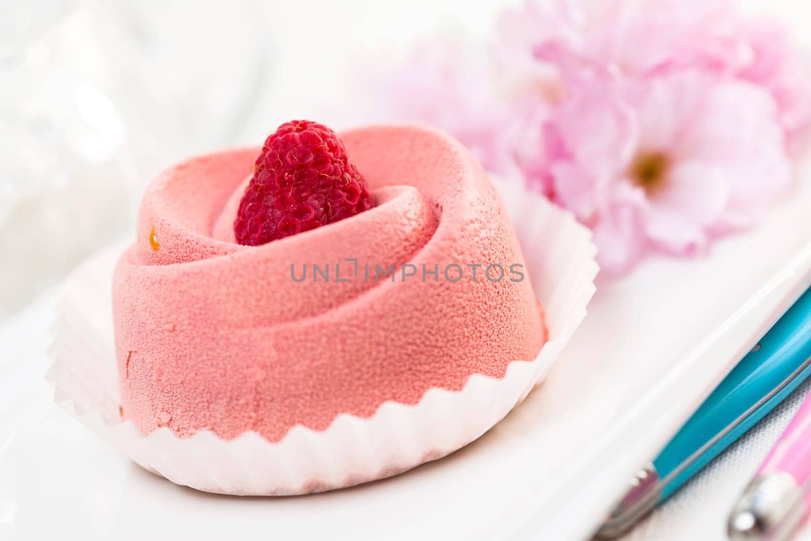 Closeup of pink raspberry mousse dessert with cherry blossom