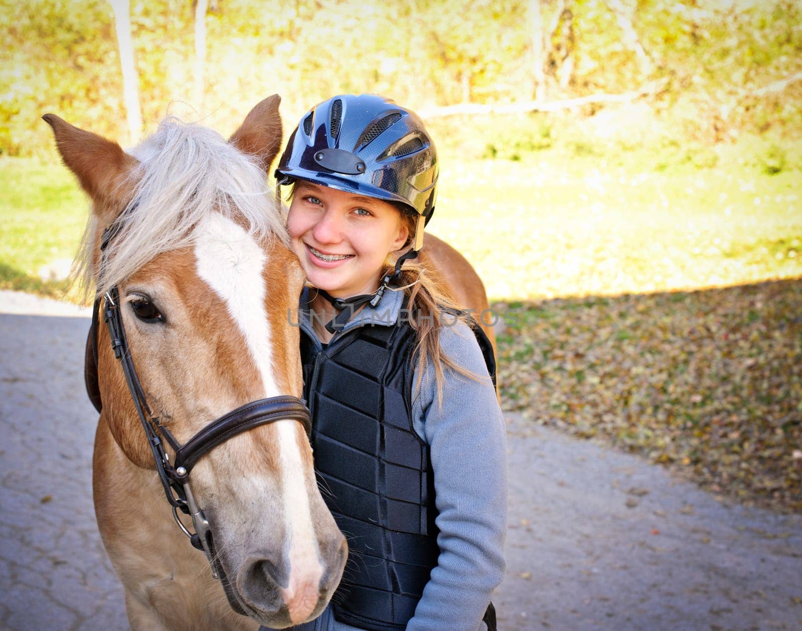 Portrait of teenage girl with horse outdoors on sunny day