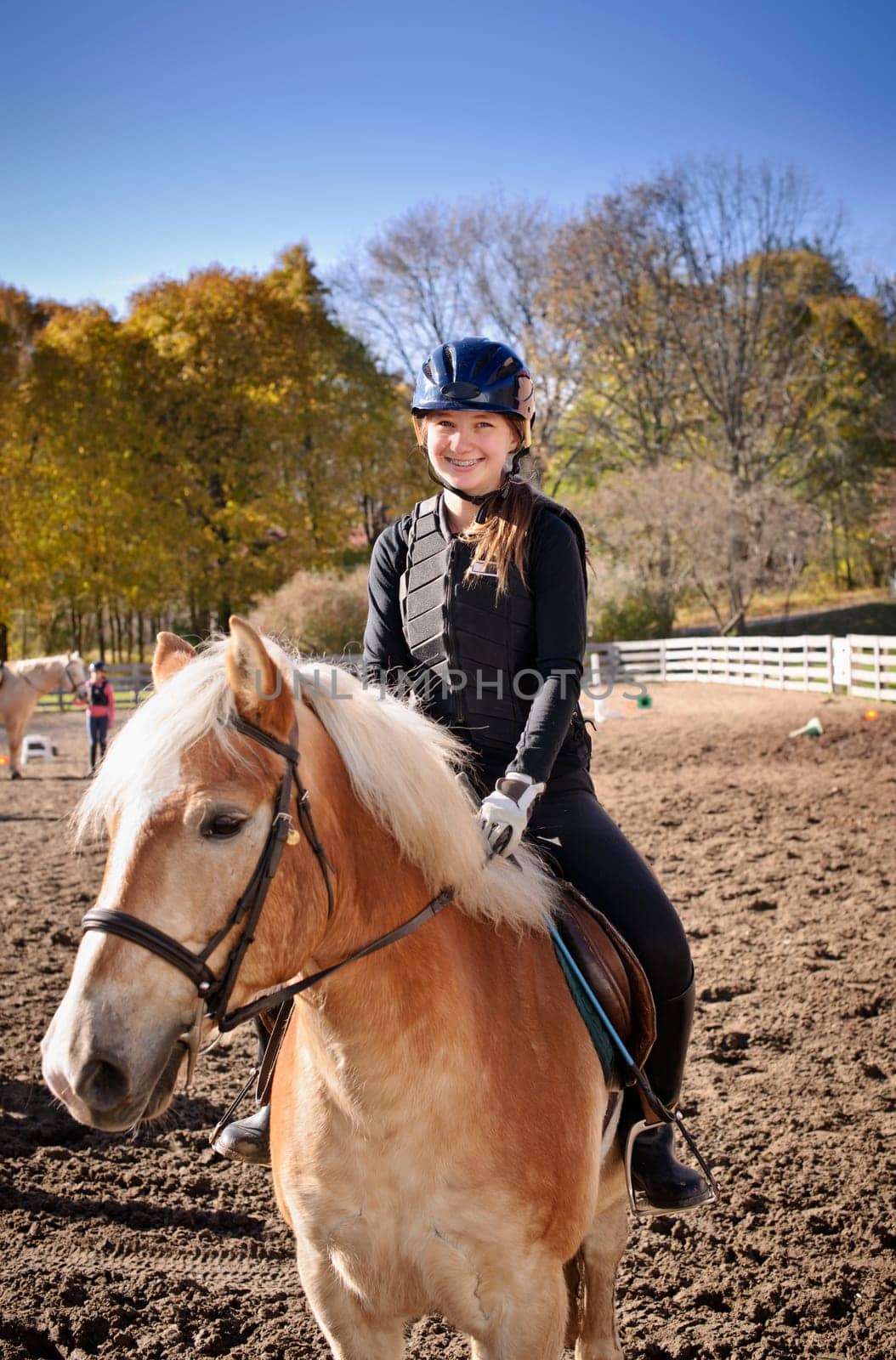 Portrait of teenage girl riding horse outdoors on sunny autumn day