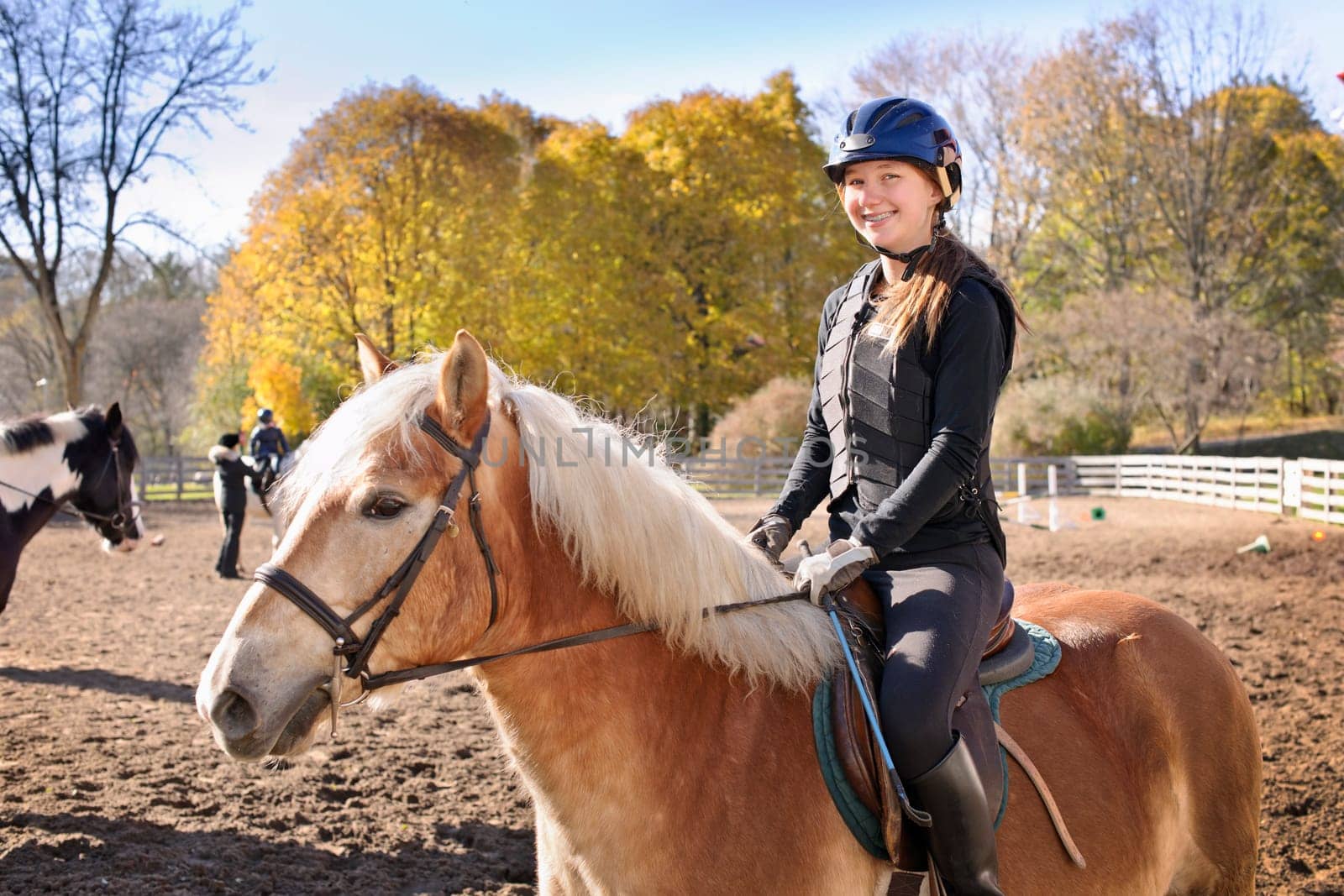 Portrait of teenage girl riding horse outdoors on sunny autumn day