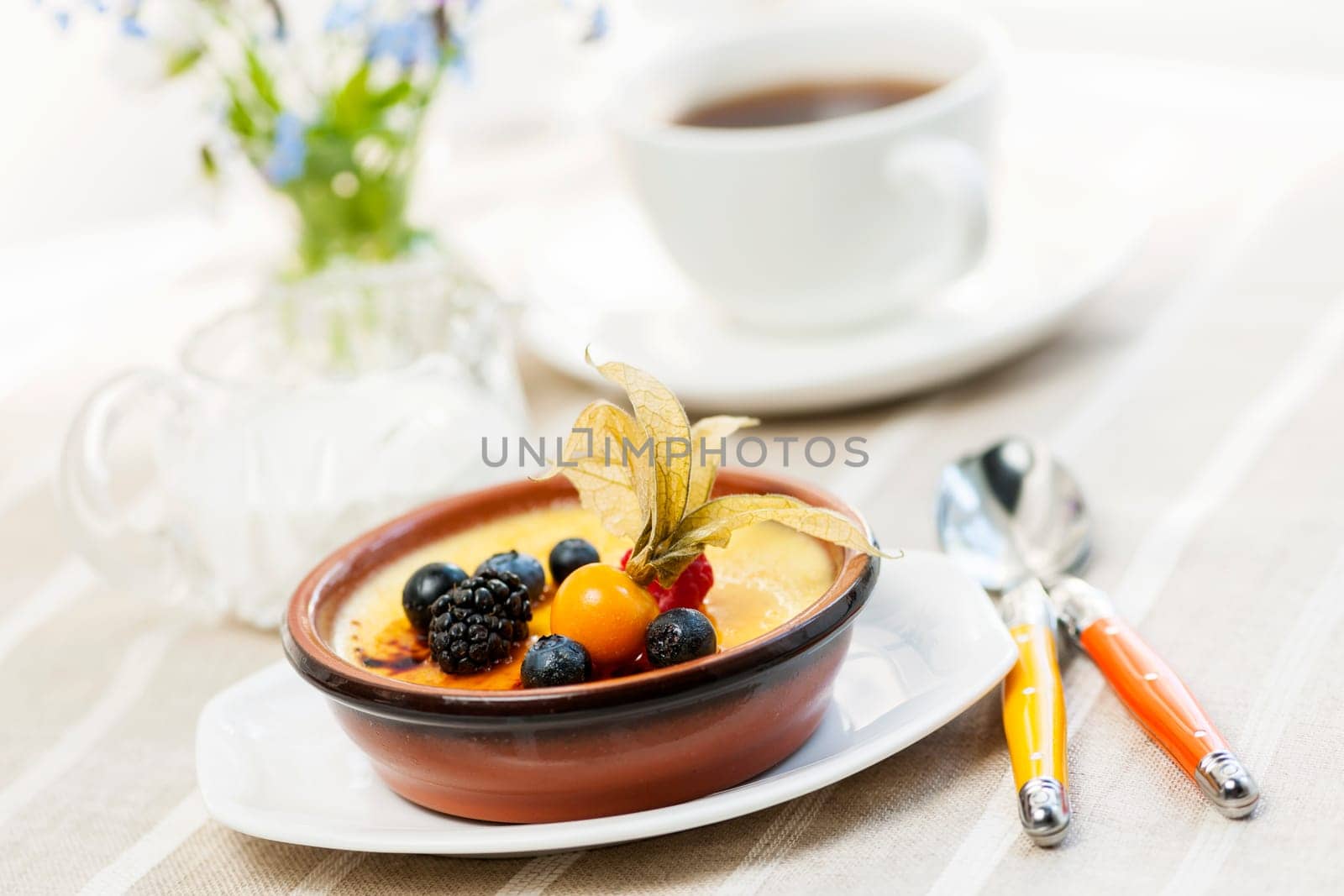 Sweet creme brulee dessert topped with fresh berries and coffee