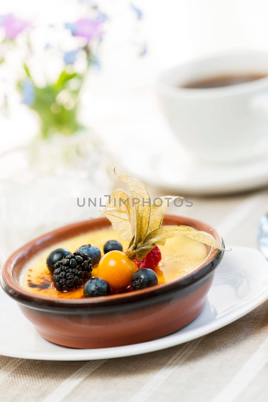 Sweet creme brulee dessert topped with fresh berries and coffee