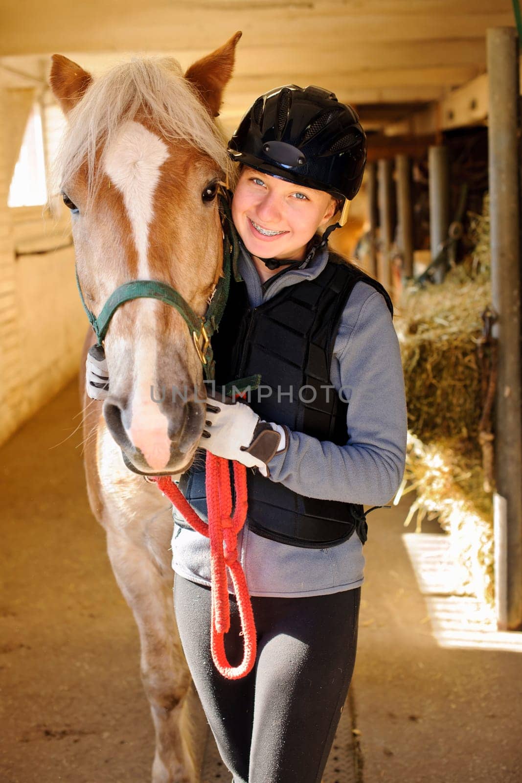 Young female rider with horse inside stable