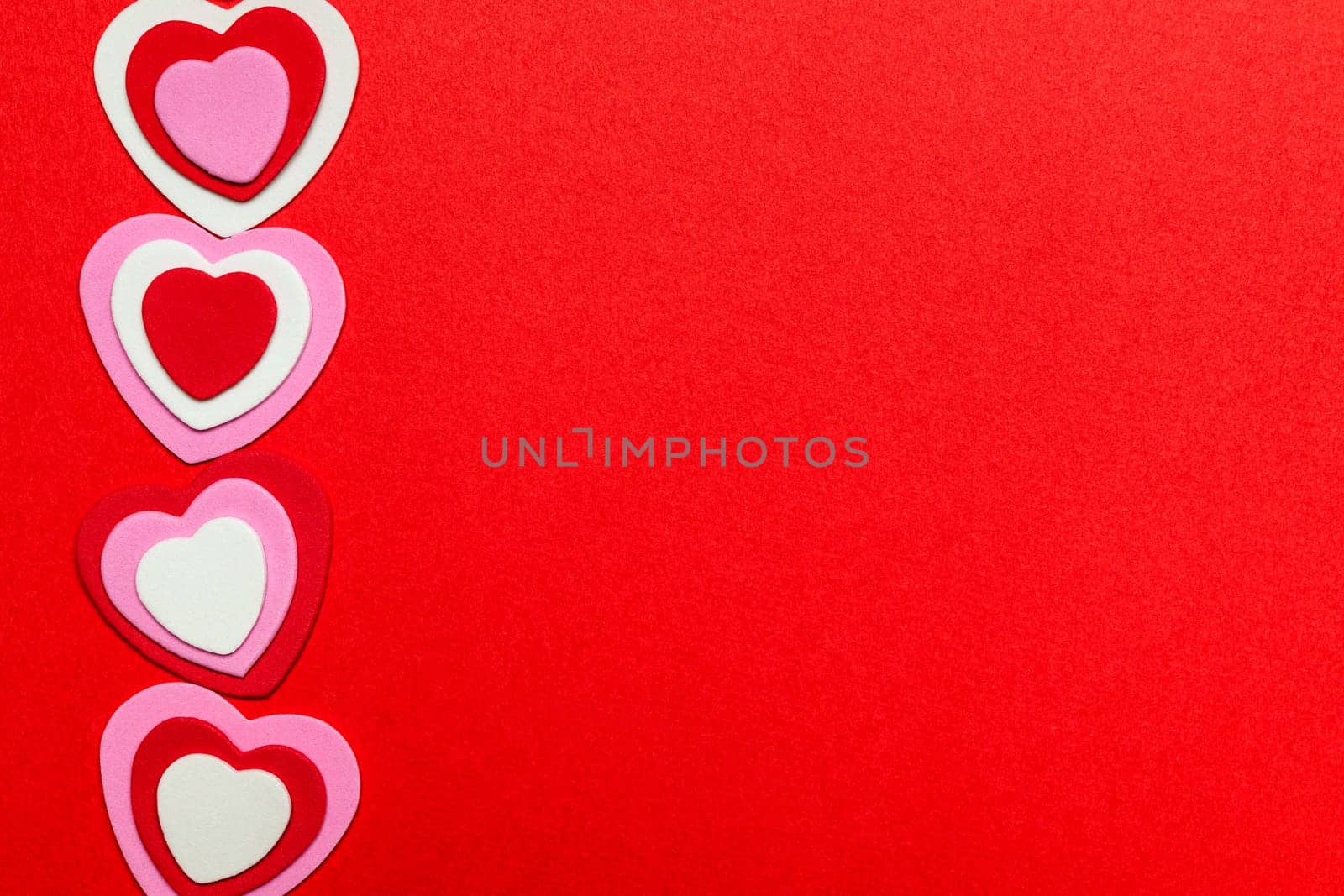 Border of romantic red pink and white hearts for Valentines day on crimson background