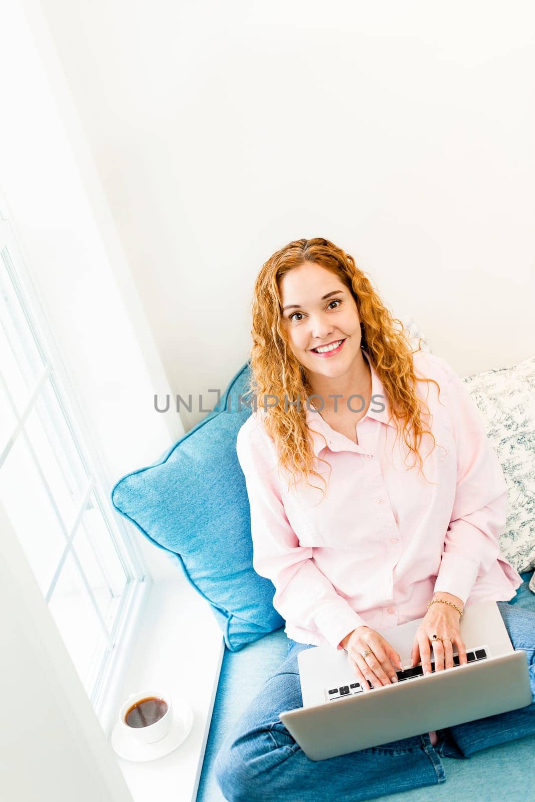 Caucasian woman with laptop computer looking up sitting on couch at home