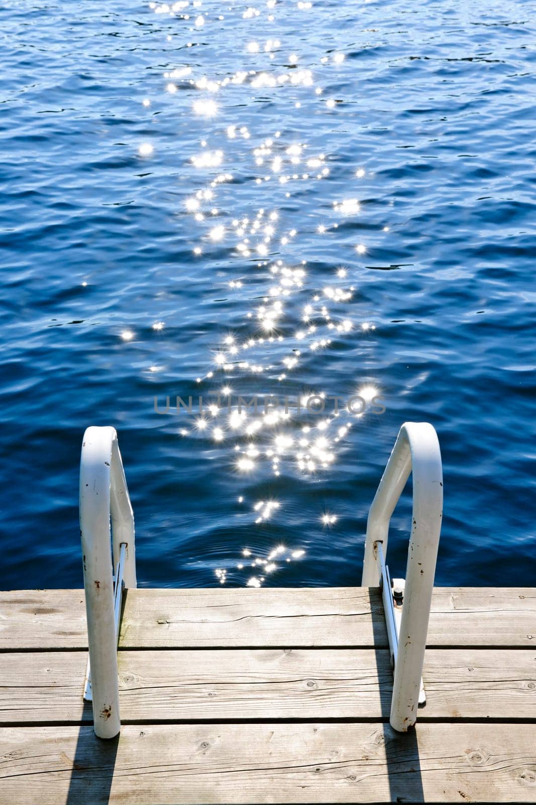 Dock and ladder on calm summer lake with sparkling water in Ontario Canada