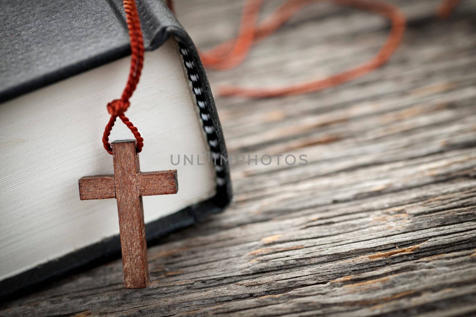 Closeup of wooden Christian cross necklace next to holy Bible